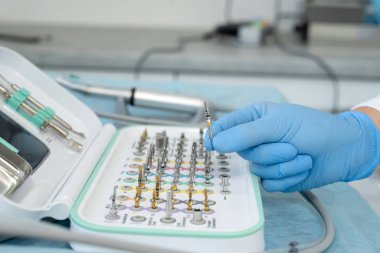 Klinikteki yaşlı bir kadın hastayı muayene etmek için tepsideki araç ve diğer erişimleri alan dişçi ya da asistan.