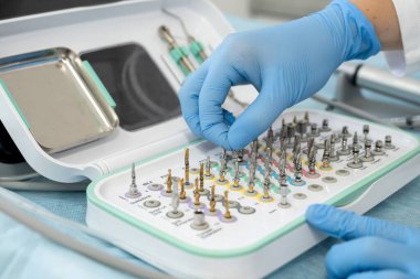 Klinikteki yaşlı bir kadın hastayı muayene etmek için tepsideki araç ve diğer erişimleri alan dişçi ya da asistan.