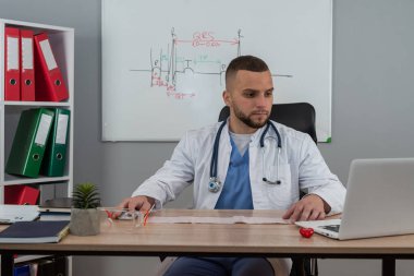 Genç doktor ya da pratisyen hekim klinikteki hasta dosyalarında çalışıyor. Hastalık tedavisi