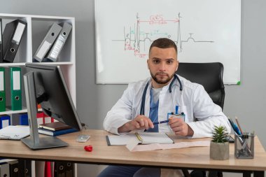 Genç doktor ya da pratisyen hekim klinikteki hasta dosyalarında çalışıyor. Hastalık tedavisi