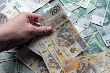 Erkek, 100 Polonyalı zloti parayı elinde tutuyor. Kaydetme veya gönderme kavramı