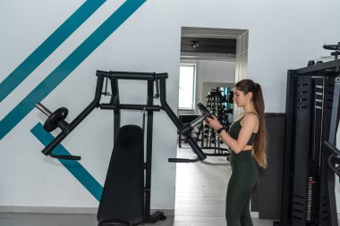 Kafkasyalı sporcu kadın spor salonunda egzersiz makinesiyle egzersiz yapıyor. Herkes için spor.