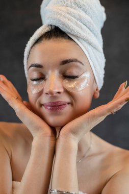 Karanlıkta izole edilmiş mükemmel cilt için göz bantlarıyla yaşlanma karşıtı ameliyatlar yapan güzel bir kadının portresi. Cilt bakımı kavramı