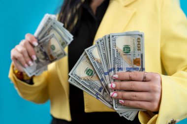 Neşeli genç bayan bir dolar nakit parayı mavi ile izole ediyor. Finansal iş konsepti, bahis ve kazanma