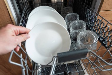 Erkek eli, bulaşık makinesinden temiz bulaşık takımı alıyor. Mutfak aletleri, yaşam tarzı.