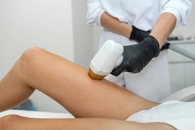 Şu anda bir kadın, profesyonel bir tıbbi ortamda rahatça yerleştirilirken bacaklarında gelişmiş bir lazer tedavisi uygulanıyor.