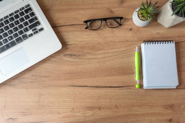Dizüstü bilgisayarı olan bir iş yeri, ofis masasında boş defter ofis malzemeleri. Yaratıcı bir geçmiş. Düz yatıyordu