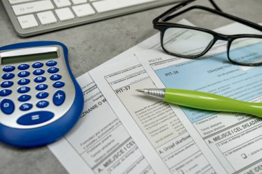 Edinilen gelir beyanı PIT vergi cilası formu, masadaki kalem hesap makinesi klavyesi. Vergilendirme kavramı