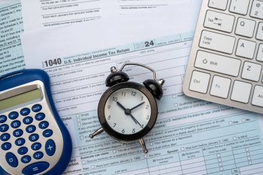 Masasında klavye hesap makinesi ve diğer ofis malzemeleri olan 1040 vergi formu var. Vergilendirme kavramı