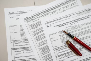 PIT-11 cila vergi formları muhasebeci masasında, kalem kapaklı. Vergi zamanı