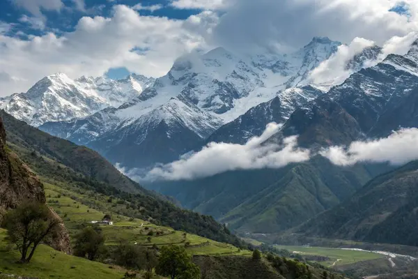 Sahnede, arka planda görkemli bir şekilde yükselen güzel karlı bir sıradağ var. Önplanda huzurlu bir nehir akıyor.