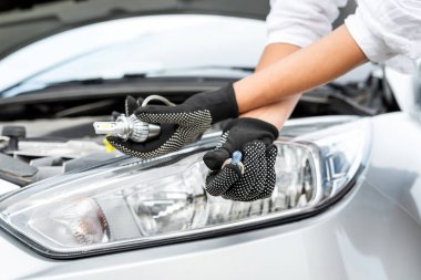 Arabada yenisi için ampulü tut. Auro tamir konsepti. Bir adam araba tamir ediyor.