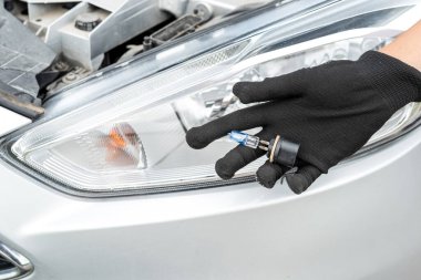  Bir adam arabanın ampulünü değiştiriyor, yolcu arabasının farında lamba tamir ediyor.