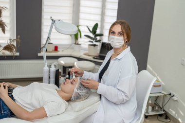 Güzellik uzmanı, kaplıcada genç ve güzel bir kadının yüzüne kimyasal peeling uyguluyor. Cilt tazeleme kavramı