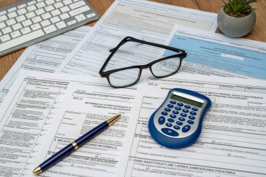 Calculating taxes in Poland, Pit different form with pen calculator glasses on desk business income