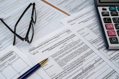 Calculating taxes in Poland, Pit different form with pen calculator glasses on desk business income