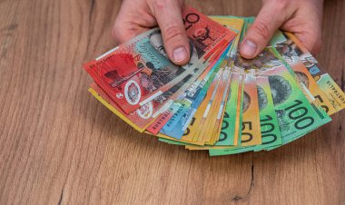 Avustralya Doları 'ndaki banknotları tahta masa arkasında tutan bir iş adamı. Finansal tasarruf kavramı