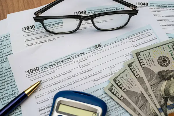 Gözlük, kalem, dolar ve vergi formu. Masada 1040 kalem hesap makinesi var. Vergi, vergi yükü. Yıllık rapor