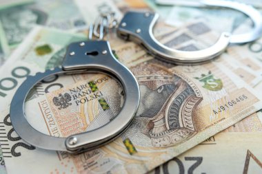 Zloty pln paralı kelepçeler masanın üstünde. Ekonomik suç kavramı