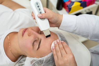  Spa stüdyosundaki güzellik uzmanı ultrasonla yüz bakımı yaptırıyor. Yüz tedavisi kavramı