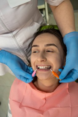 Diş fırçasını diş hekimindeki kadın hastasına mükemmel temizlik ve hijyen sağlamak için kullanan bir dişçi. Klinikte profesyonel diş temizliği.