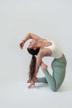 Genç bir kadın esneme egzersizi yapıyor, beyaz arka planda izole edilmiş. Spor ve spor konsepti