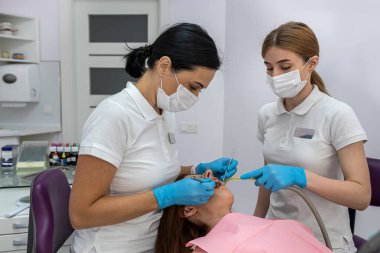 young female patient being examined and treated by a female dentist and an assistant in a dental clinic. treatment of the oral cavity