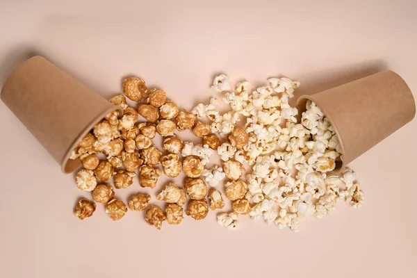 Two types of popcorn in two paper cups. Caramel-covered and salted popcorn. Popcorn spilled out of cups and mixed. Shallow depth of field, top view.