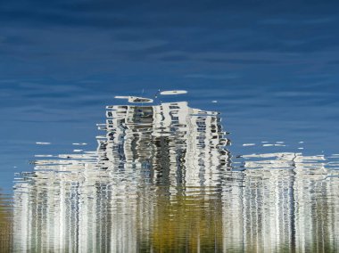 Blue water reflex background of town. Abstract reflection and abstract inspection elements in water. City, buildings, house elements distorted in the river. Rippled water texture. Disordered surface.  clipart