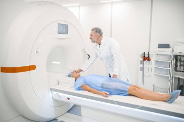 - MRI. Erkek doagnostik uzmanı hastayı MR 'a hazırlıyor.