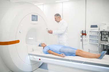- MRI. Erkek doagnostik uzmanı hastayı MR 'a hazırlıyor.