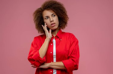 Düşüncelerle. Kırmızı ceketli güzel kıvırcık saçlı kadın düşünceli görünüyor.