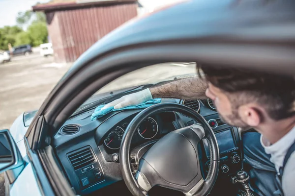 stock image Service station worker in the work glove wiping a dirty car dashboard with a microfiber cloth