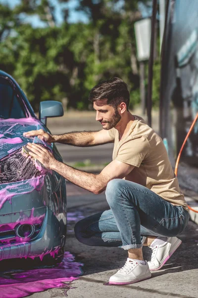 stock image Focused car wash service worker wiping the headlight of motor vehicle with a microfiber sponge