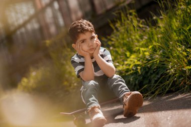Yalnız hissediyorum. Koyu saçlı çocuk oturur ve yalnız hisseder.