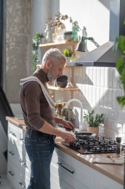 Yemek pişirmek. Adam sobanın yanında duruyor ve bir şeyler kızartıyor.