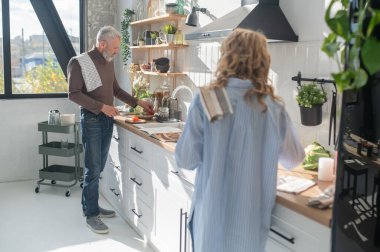 MMan mutfakta. Mutfakta yemek pişiren gri saçlı olgun bir adam.