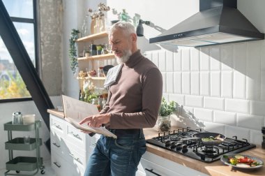 Resepsiyon aranıyor. Sakallı, olgun bir adam yemek kitabında resepsiyon arıyor.