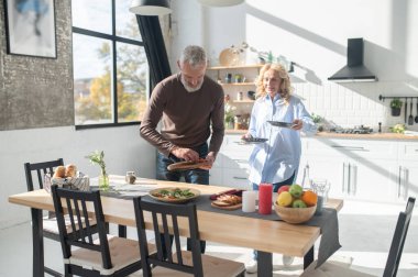 Preparing table for dinner. Man and woman serving the table for dinner