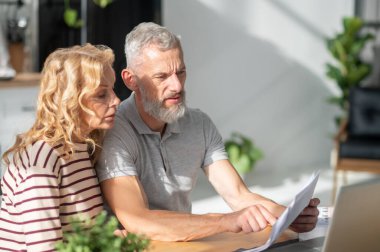 On internet. A mature couple scrutinizing the papres and searching internet