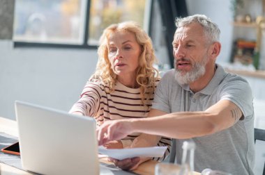 Work from home. Two people at the laptop looking involved and discussing something