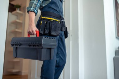 Cropped photo of a serviceman with the toolbox walking into the room in a customer apartment