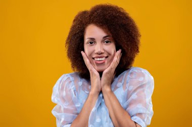 Suprised. Pretty curly-haired woman in white blouse looking surprised