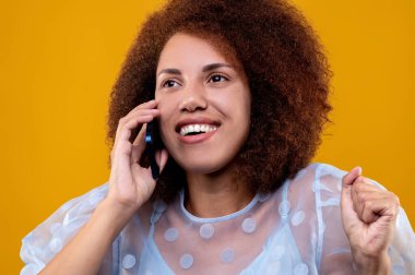 Phone call. Curly-haired young woman talking on the phone