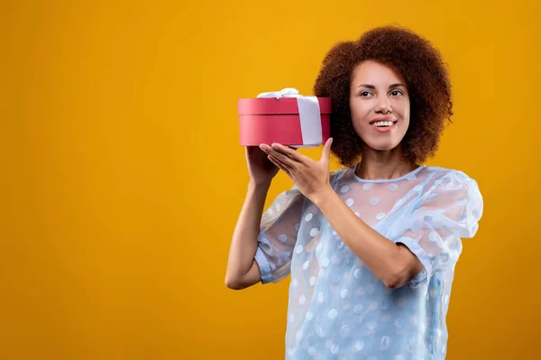 Birthday gift. A young woman holding a gift box and looing happy