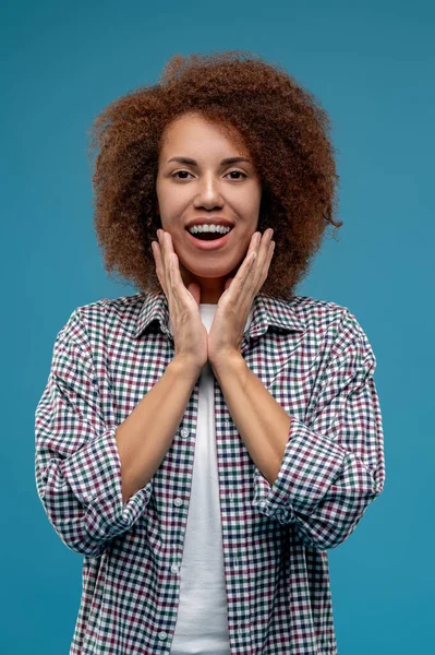 Good mood. Curly-haired young woman looking contented and smiling