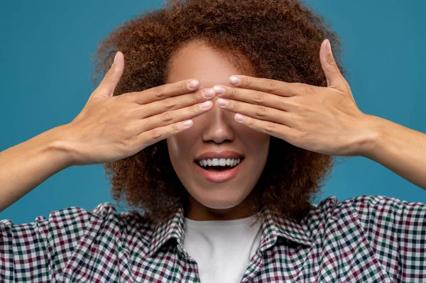 Closing eyes. Young woman in plaid shirt closing her eyes with hands