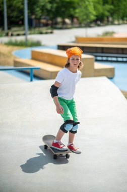 Full-length portrait of a serious concentrated young skateboarder in protective gear stepping on his skateboard