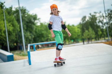 Full-size portrait of a serious young professional skateboarder in protective gear riding alone on his skateboard