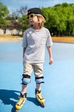 Full-size portrait of a kid in the sunglasses and knee pads standing on the roller skates